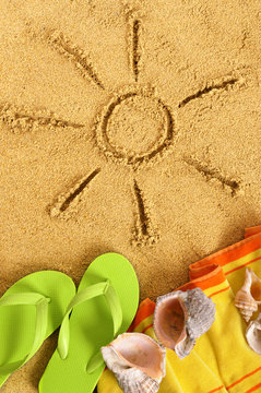 Summer sun drawing drawn on a sand beach with towel seashell and flip flop sandals happy relaxed vacation holiday photo vertical