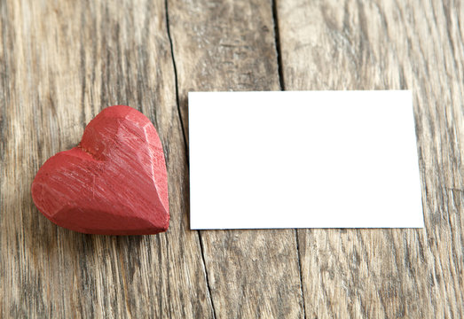 cœur sculpté et carton blanc sur fond de bois
