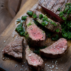 Close-up of sliced medium rare beef steak with chimichurri sauce