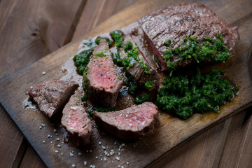 Medium rare grilled beef steak with chimmichurri sauce, close-up