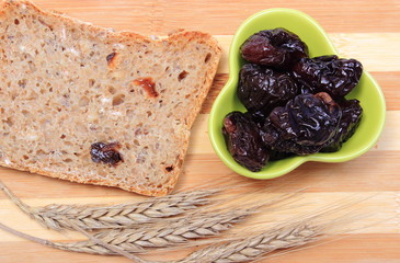 Baked wholemeal bread, dried plums and ears of wheat
