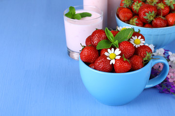Fresh strawberries in a cup, a bowl with chamomile 