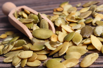 Pumpkin seeds with spoon on wooden background