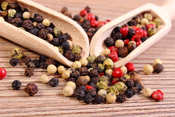 Fresh colored pepper with spoon on wooden background