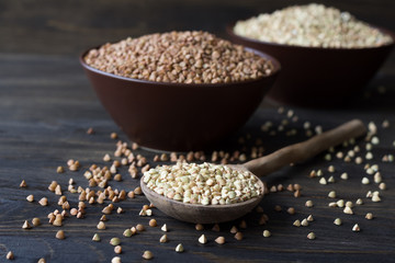 Green and brown buckwheat in ceramic bowls on a wooden surface 