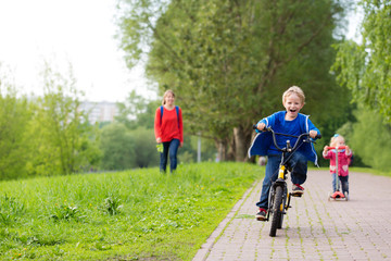 happy kids riding scooter and bike in the park