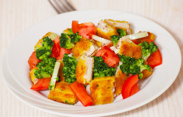 Fresh vegetable salad with fried breaded fish fillets