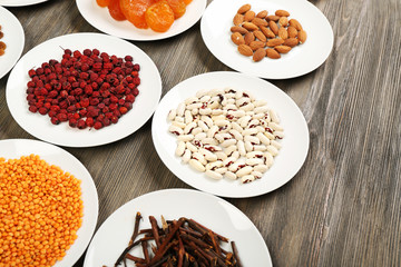 Different products on saucers on wooden table, closeup