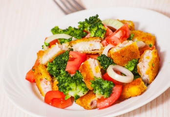 Fresh vegetable salad with fried breaded fish fillets