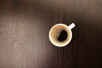 Cup of coffee on wooden table, top view