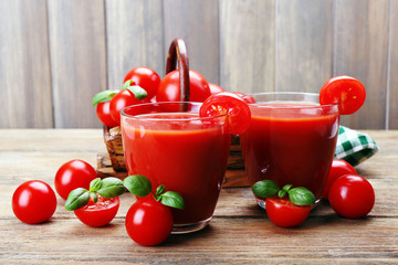 Glasses of tomato juice with vegetables on wooden background