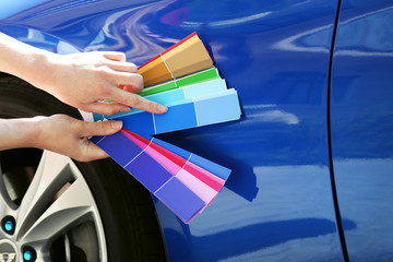 Female hands with paint samples choosing color for painting car, closeup