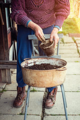 Old woman filling a pot with fresh soil. Symbol of spring and clean eating concept.