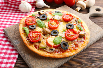 Tasty pizza with vegetables and basil on table close up