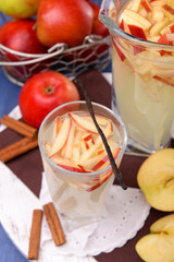 Glass and carafe of apple cider with fruits and spices on table close up
