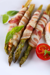 Dish of asparagus with bacon and egg in plate on table, closeup