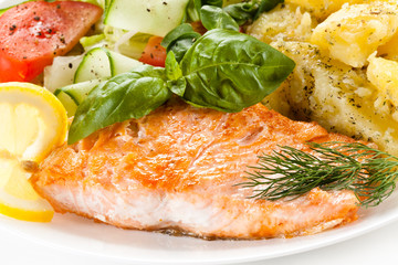 Fried salmon and vegetables on white background 