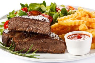 Grilled steak, French fries and vegetables on white background 