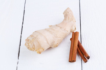 Fresh ginger with cinnamon on wooden table.