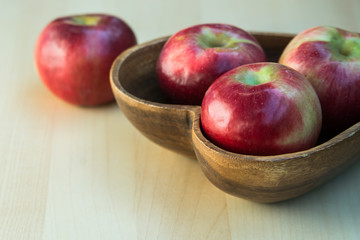 Apples in the wooden heart shape plate on the table, close up