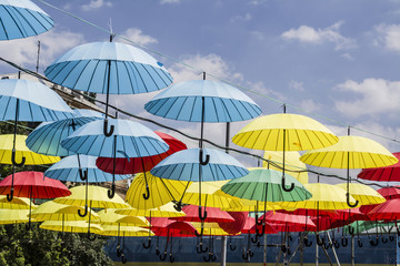 Obraz na płótnie Canvas colored umbrellas hanging from a rope sky background
