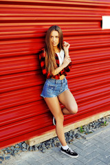 Full length portrait of a beautiful sexy woman posing by a red w