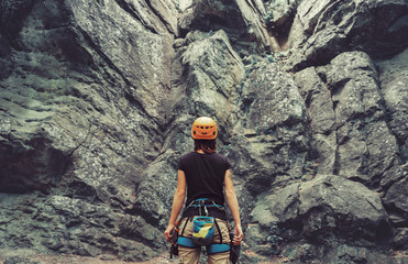 Bergsteigerfrau steht vor einem Steinfelsen im Freien