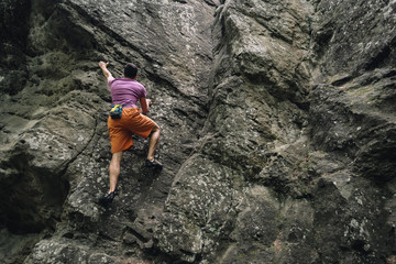 Young man climbing on stone rock