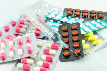 Medicines, pills and syringe on white background
