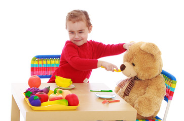 Little girl plays with a teddy bear