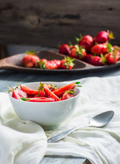 juicy red strawberry slices in a white plate, blue background, h