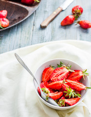 organic red strawberry slices in a white plate, blue background,