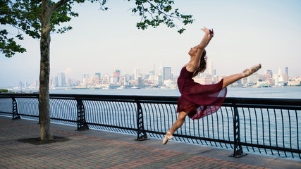Fototapeta premium Defocused young beautiful ballerina dancing along the New Jersey waterfront. New York.