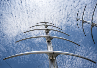Masts like herringbone and Radar Communication Tower on a Yacht. Detail of luxury white yacht with security camera and navigation equipment, radar and antennas on blue sky with clouds