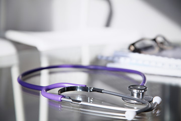 Purple stethoscope on the glass desk