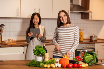 Two female friends are cooking together at home