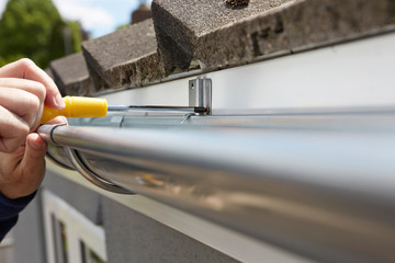 Close Up Of Man Replacing Guttering On Exterior Of House - obrazy, fototapety, plakaty