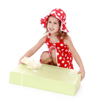 Beautiful girl in a red dress and hat polka dot bent down to exa