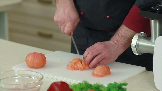 Frontal shot of chef cutting up peeled tomatoes
