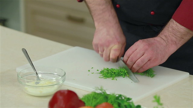 Close-up of a chef chopping dill. Frontal shot