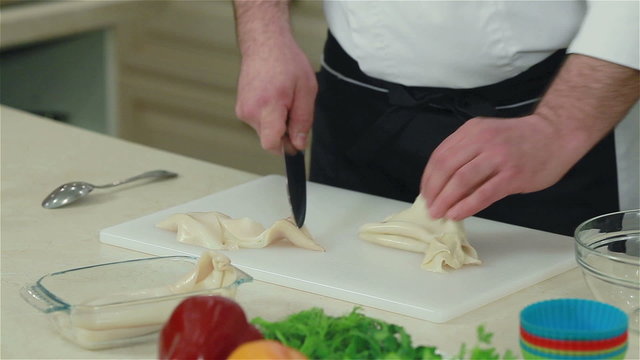 Close-up of a chef cutting squid. Frontal shot