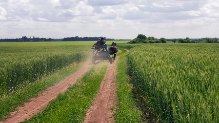 Wooden cart rides on the spring farm road along the field