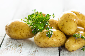 Fresh young potatoes on a wooden background with herbs