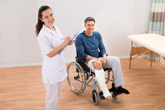 Doctor With Patient Writing On Clipboard