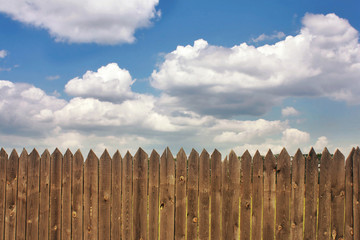 Obraz premium Dark old wood fence is against the blue sky