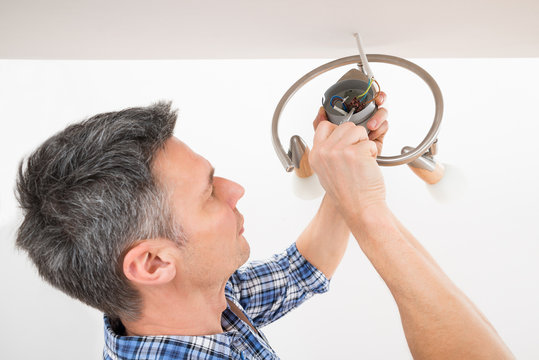Electrician Fixing Light On Ceiling