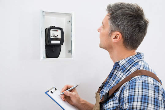Technician Taking Reading Of Electric Meter