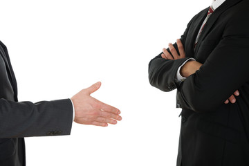 Person Offering Handshake To Businessman With Arm Crossed