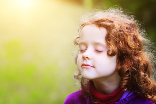 Little girl closed her eyes and breathes the fresh air in the pa