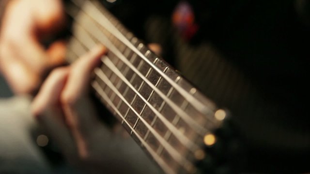 Musician playing five string electric bass guitar; cluseup